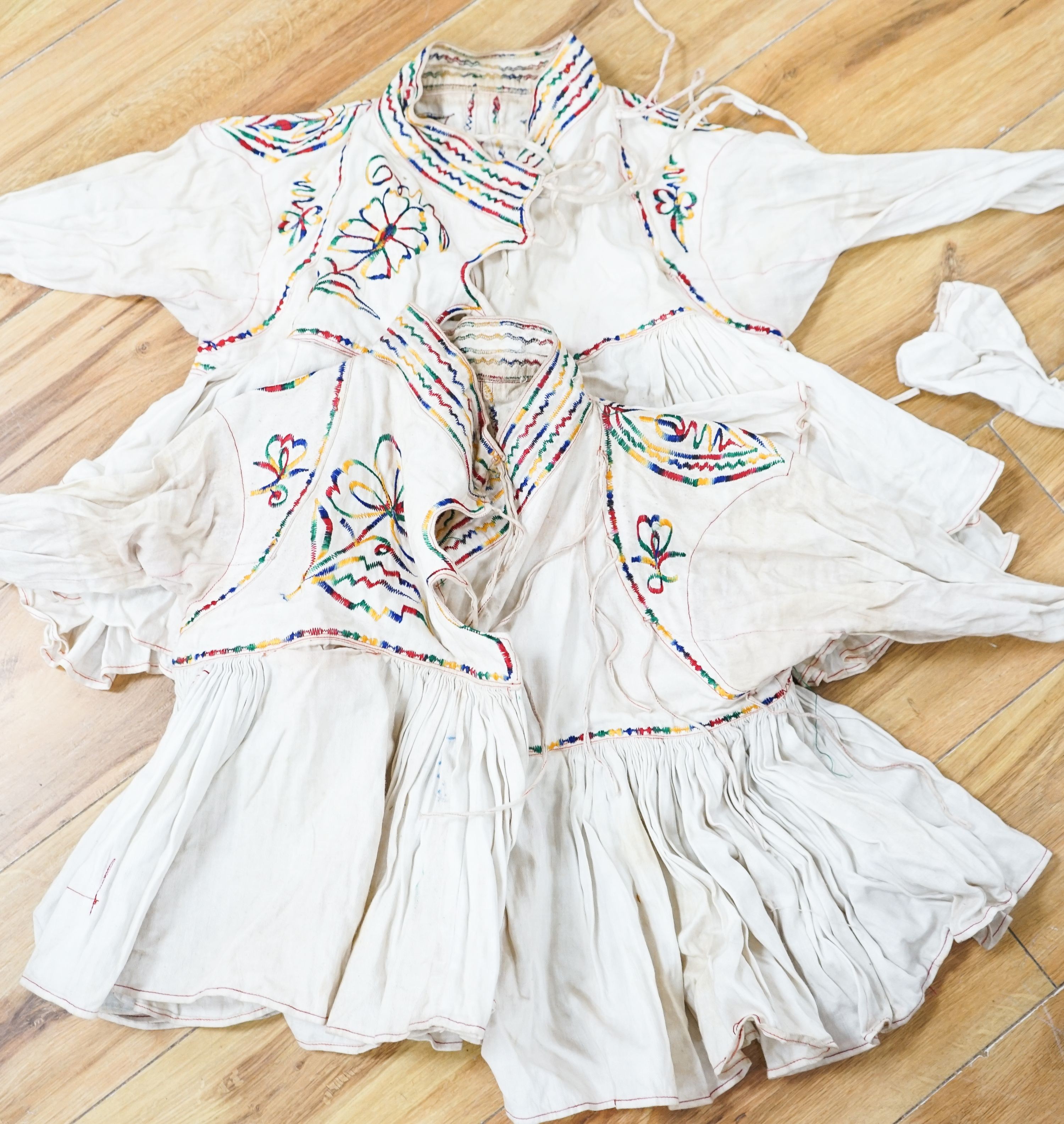 Eight white linen and multi-coloured embroidery blouses
